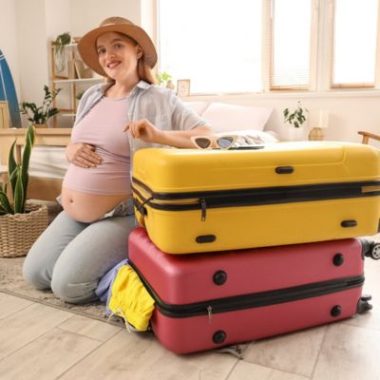 Pregnancy travel carry-on essentials including compression socks, a neck pillow, ginger chews and a portable fan.