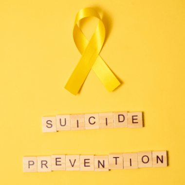 A yellow ribbon and a sign that reads Suicide Prevention.